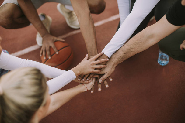 Overhead view of basketball team holding hands over court - Фото, зображення