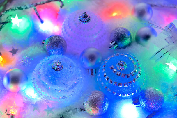 christmas baubles in snow and colorful lights - Foto, Imagem