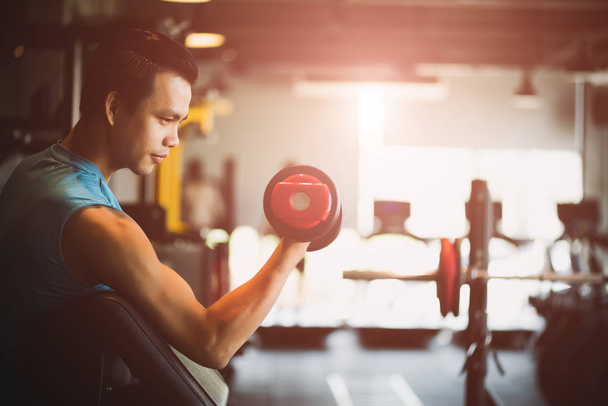 Man hand holding dumbbell exercise in gym. Fitness muscular body with set of black weights in the gym background. exercise and healthy lifestyle concept. - Photo, Image