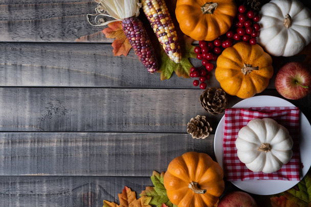 Vista superior de las hojas de arce de otoño con calabaza, manzana, maíz y bayas rojas sobre fondo de madera vieja. Concepto del día de Acción de Gracias
. - Foto, Imagen