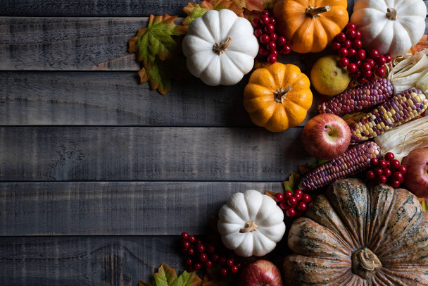 Vista superior de las hojas de arce de otoño con calabaza, manzana, maíz y bayas rojas sobre fondo de madera vieja. Concepto del día de Acción de Gracias
. - Foto, imagen