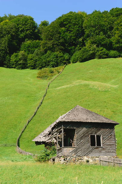 παλιό εγκαταλελειμμένο σπίτι ξύλινο με πράσινο γρασίδι λόφους στο παρασκήνιο - Φωτογραφία, εικόνα