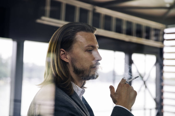 Side view at young businessman enjoying his cigar on a break - Photo, Image