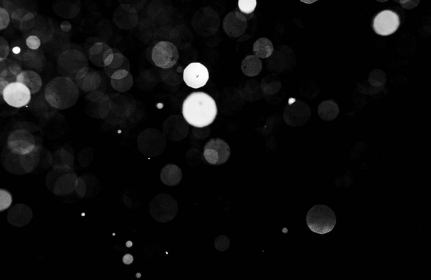 Snowstorm texture. Bokeh lights on black background, shot of flying snowflakes in the air - Photo, Image