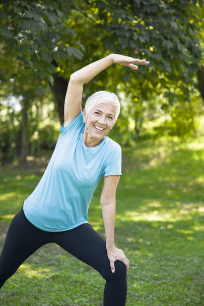 Портрет пожилой женщины, выполняющей упражнения в парке
 - Фото, изображение