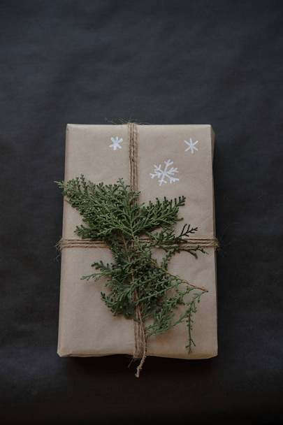 Christmas gift box on black background. Christmas present with handmade decoration. Close up. Copy space - Zdjęcie, obraz