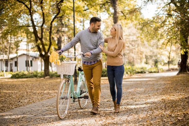 Jeune couple actif jouissant ensemble dans une promenade romantique à vélo dans le parc d'automne doré
 - Photo, image
