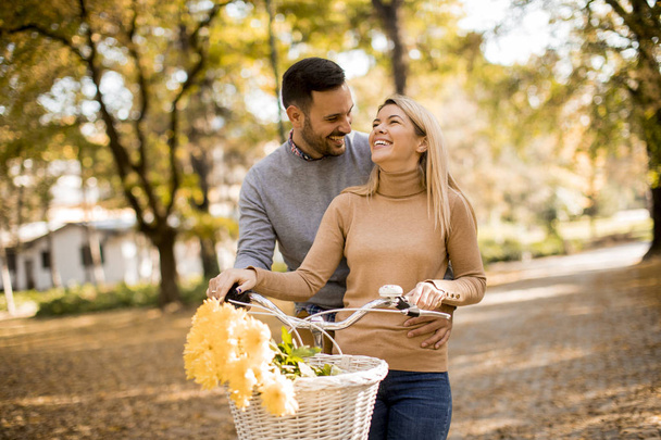 Ativo jovem casal desfrutando juntos em passeio romântico com bicicleta no parque de outono dourado
 - Foto, Imagem