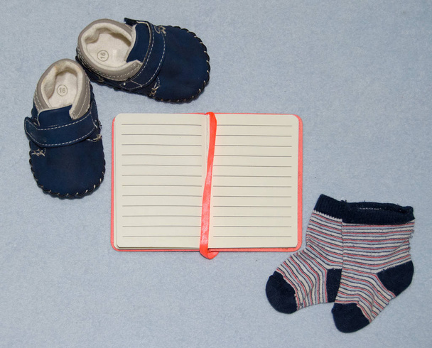 Table top view decoration baby shoes clothes notebook and toys. Flat lay, copy space - Photo, Image