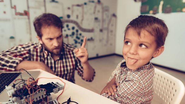 Bearded Father Help Funny Son with Robot at Home. Young Boy in Shirt. Using Laptop. Modern Hobby Concept. Modern Technology. Robot Engineering Concept. Bearded Young Man. Innovation for Fun. - Φωτογραφία, εικόνα