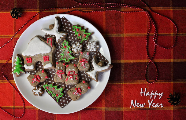 Prato festivo de Natal com biscoitos doces, casa, flocos de neve e porcos, símbolo de ano novo, cor de Natal vermelho e marrom clássico, conceito de férias de inverno, formato de cartão de saudação
 - Foto, Imagem