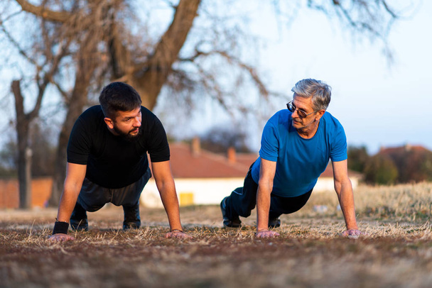 Senior father and son doing pushups on outdoor workout - Photo, Image