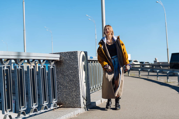 Beautiful young woman wearing oversize coat walking the bridge - Foto, Bild