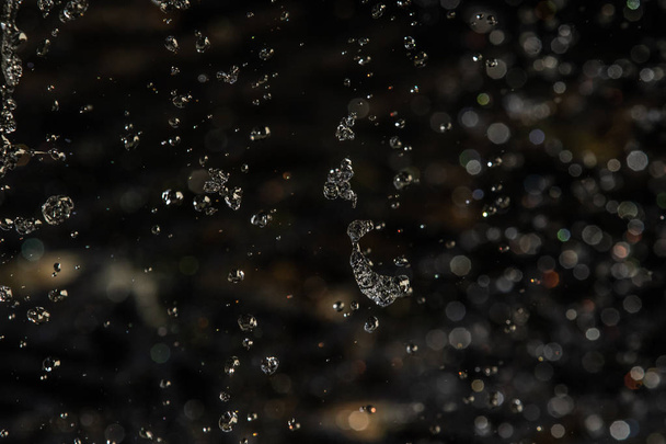 Splash Water στο σκοτάδι με μια σταγόνες του νερού που φέρουν, defocused bokeh. - Φωτογραφία, εικόνα