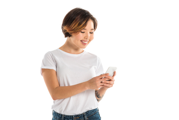 smiling young woman using smartphone isolated on white - Foto, afbeelding