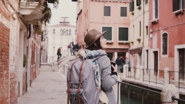 Happy beautiful tourist girl taking smartphone photos walking at amazing water canal street in Venice Italy slow motion. - Felvétel, videó