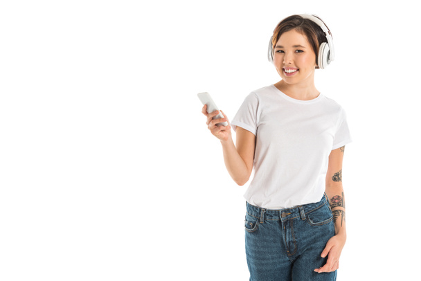 beautiful young woman wearing headphones, listening music and using smartphone isolated on white - 写真・画像