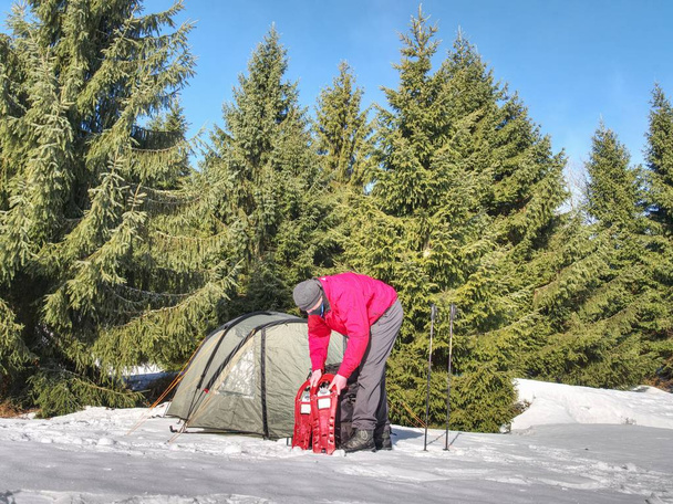 Ihminen asettaa lumikengät ja vaellus tikkuja kävellä. Valo teltta asetettu vuorille. Talvimatka
.  - Valokuva, kuva