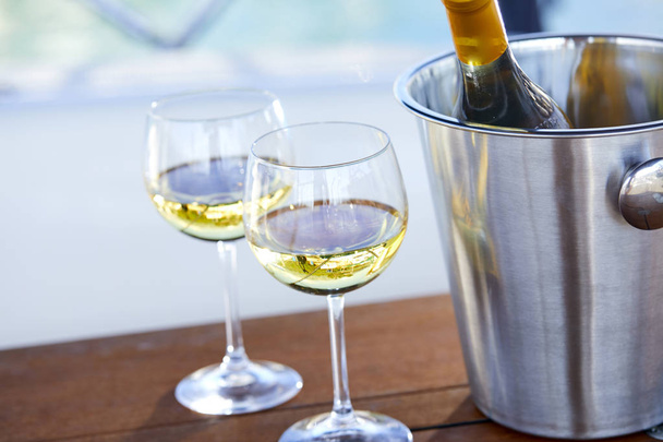 Paar Weingläser und Eimer mit Weißweinflasche auf Jacht - Foto, Bild