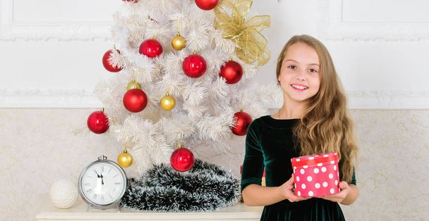 Merry christmas concept. Dreams come true. Best for our kids. Child celebrate christmas at home. Favorite day of the year. Kid girl near christmas tree hold gift box. Time to open christmas gifts - Photo, image