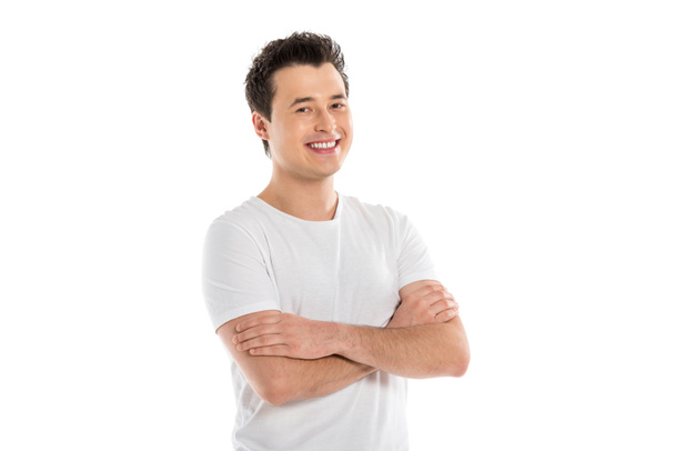Portret van knappe Glimlachende man met gekruiste armen kijken camera geïsoleerd op wit  - Foto, afbeelding