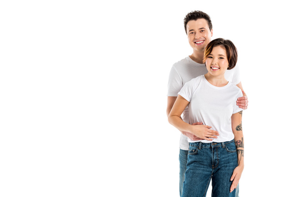 happy boyfriend looking at camera and hugging smiling girlfriend isolated on white - Foto, Imagen