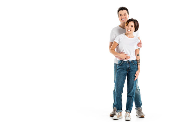 loving boyfriend looking at camera and hugging smiling girlfriend isolated on white - Foto, imagen
