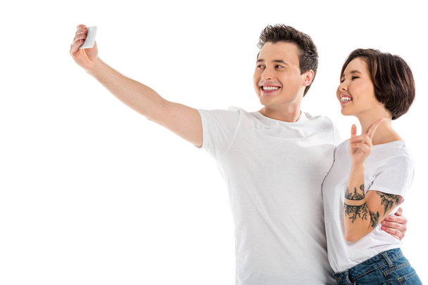 cheerful couple taking selfie on smartphone isolated on white - Zdjęcie, obraz