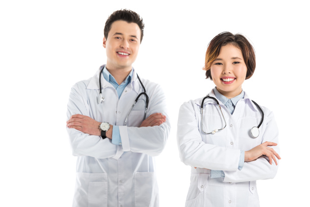 smiling female and male doctors looking at camera with arms crossed isolated on white - Photo, Image