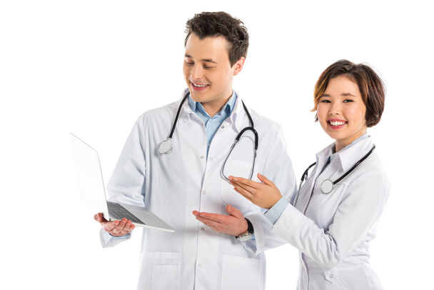 sonrientes médicos femeninos y masculinos utilizando portátil aislado en blanco
 - Foto, Imagen