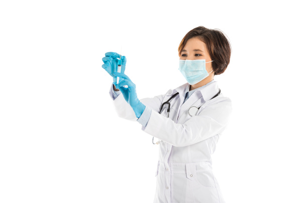  skoncentrowany, lekarka maseczkę medyczną, trzymając strzykawkę na białym tle - Zdjęcie, obraz