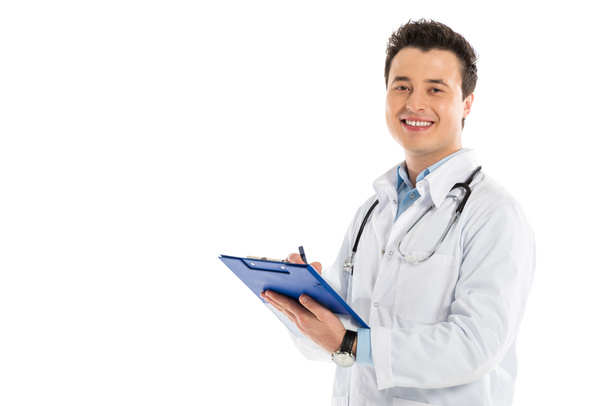 sonriente médico masculino escribiendo diagnóstico y mirando a la cámara aislada en blanco
 - Foto, Imagen