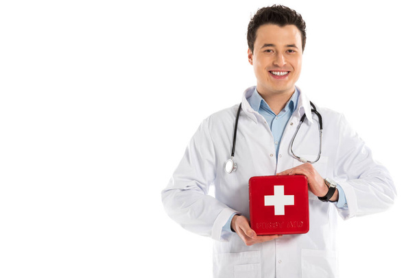 pohledný muž lékař drží lékárnička a při pohledu na fotoaparát izolované na bílém - Fotografie, Obrázek
