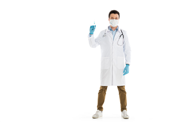 male doctor in medical mask standing and holding syringe isolated on white - 写真・画像
