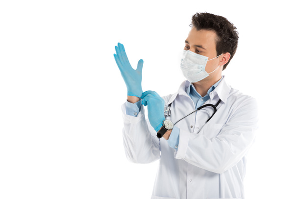 handsome male doctor putting on rubber gloves isolated on white - Foto, Imagen
