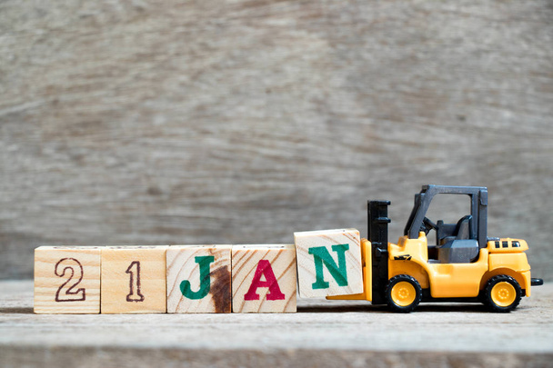Toy forklift hold block N to complete word 21jan on wood background (Concept for calendar date in 21 month January) - Photo, Image