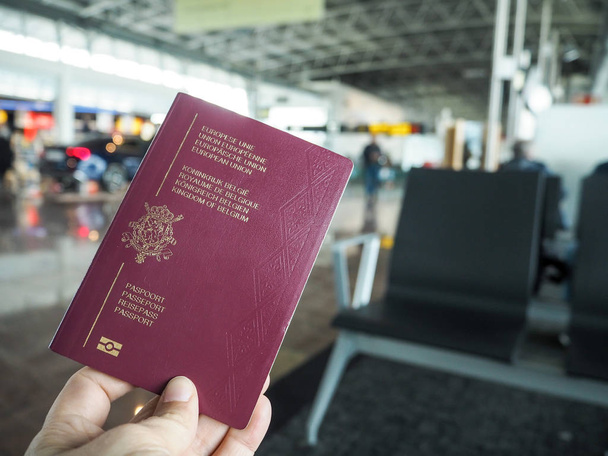 Person holding a Belgian passport in a airport terminal - Photo, Image