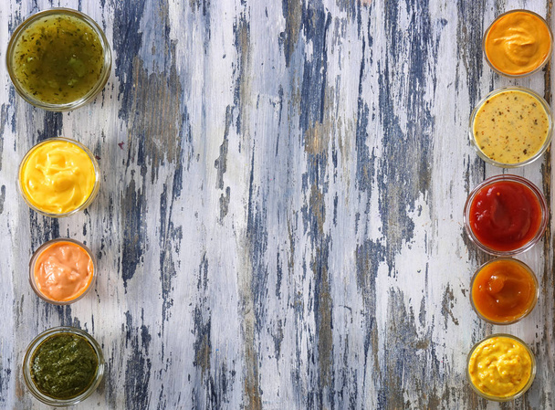 Verschillende lekkere sauzen in kommen op houten tafel - Foto, afbeelding