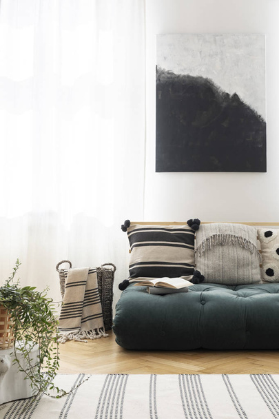 Plant near green futon with patterned cushions in natural living room interior with poster. Real photo - Fotografie, Obrázek