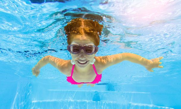 Lachende meisje onderwater zwemmen in zwembad - Foto, afbeelding