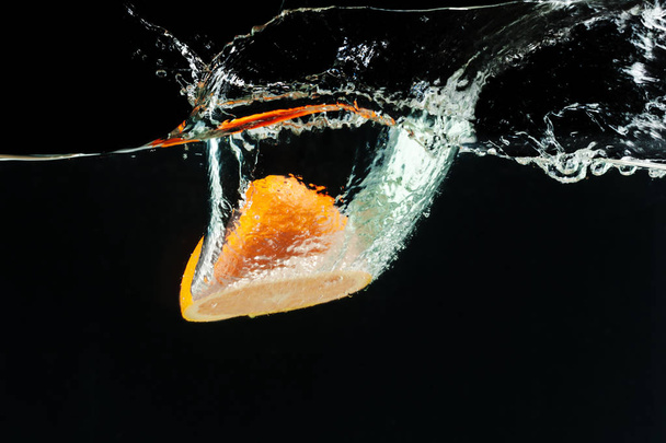 Oranssi putoaa veteen ja tekee roiskeita
 - Valokuva, kuva