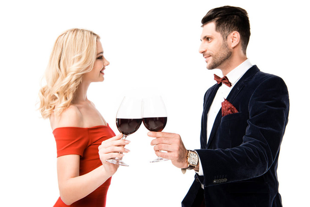 Feliz pareja sonriente tintineo vasos con vino tinto aislado en blanco
 - Foto, Imagen
