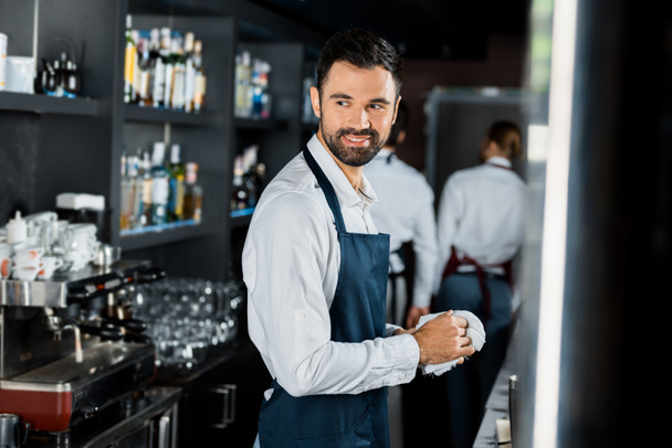 sorrindo bonito bartender polimento de vidro no local de trabalho
  - Foto, Imagem