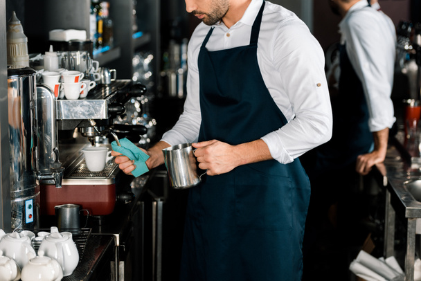 cropped view of barman in apron preparing coffee with coffee machine - Foto, afbeelding