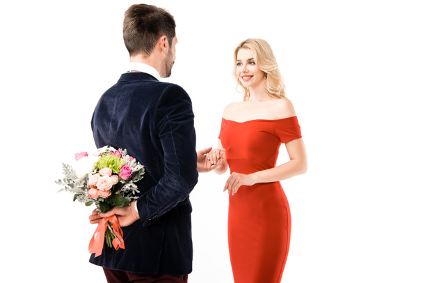 Back view of man with flowers behind back holding hands of girlfriend on white - Photo, Image