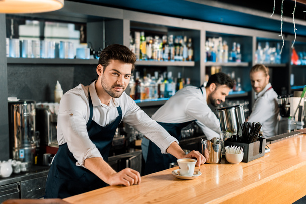 adult handsome barista in apron with coffee at wooden counter - Photo, Image