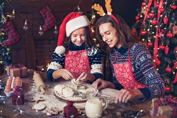 Merry Christmas and Happy Holidays. Mother and daughter cooking Christmas cookies. - Фото, изображение