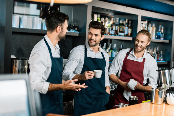 barman adulto bebiendo café y hablando con colegas en el lugar de trabajo
 - Foto, Imagen