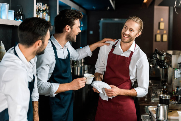 glimlachend barman drinken koffie en te praten met collega's op de werkplek - Foto, afbeelding