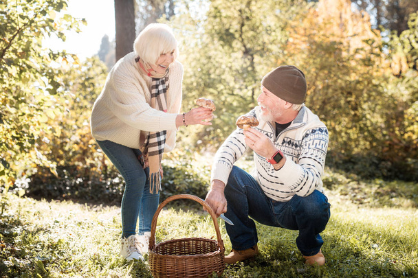 Mulher idosa agradável mostrando um cogumelo ao marido
 - Foto, Imagem